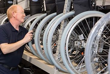 Man Lifting Wheelchair on to Racking