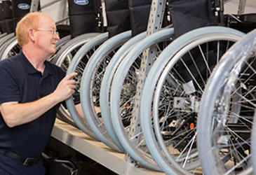 Man Lifting Wheelchair on to Racking